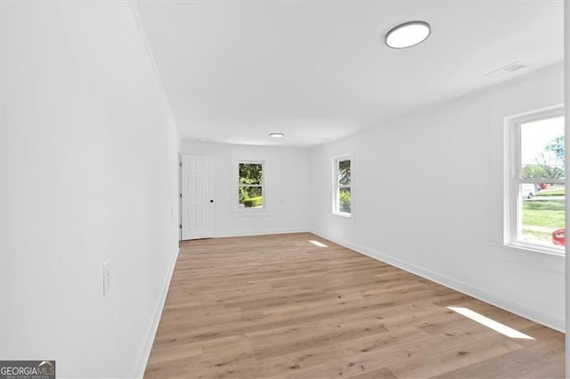 spare room with baseboards and light wood finished floors