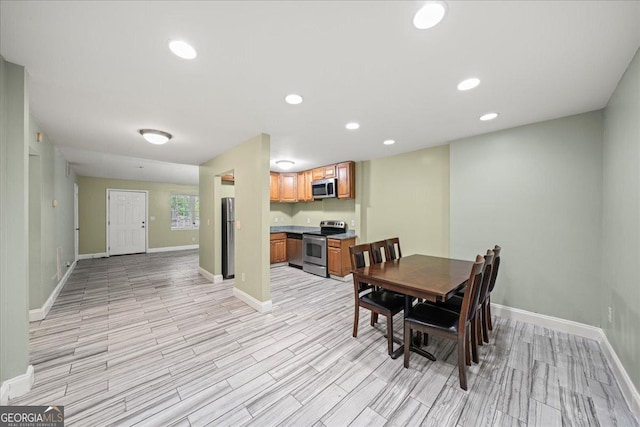 dining room with baseboards, light wood finished floors, and recessed lighting