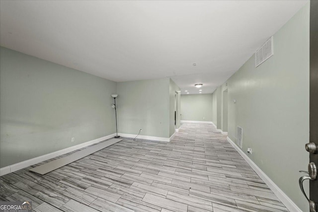 unfurnished room with light wood-style floors, visible vents, and baseboards