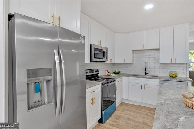 kitchen featuring light stone counters, a sink, white cabinetry, and appliances with stainless steel finishes