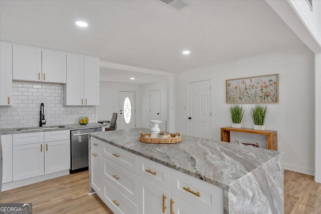kitchen featuring a sink, tasteful backsplash, visible vents, light stone countertops, and dishwasher