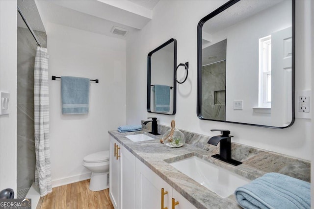 bathroom with wood finished floors, visible vents, toilet, and a sink