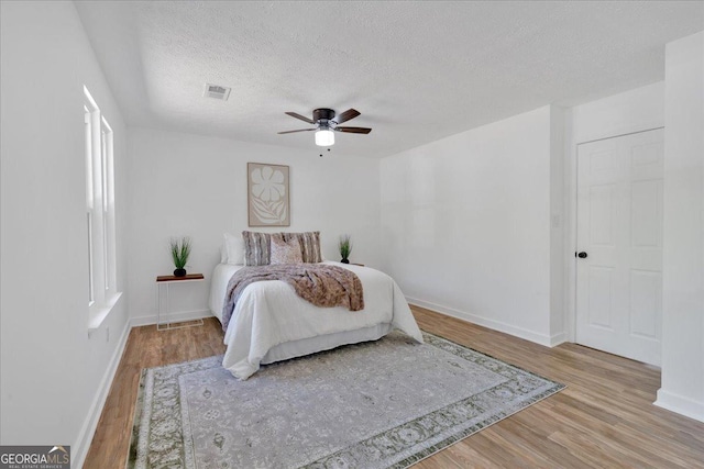 bedroom featuring baseboards, wood finished floors, and visible vents