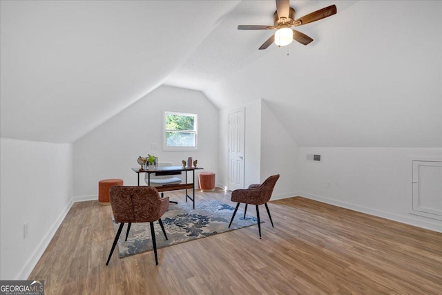 sitting room with a ceiling fan, light wood finished floors, baseboards, lofted ceiling, and visible vents