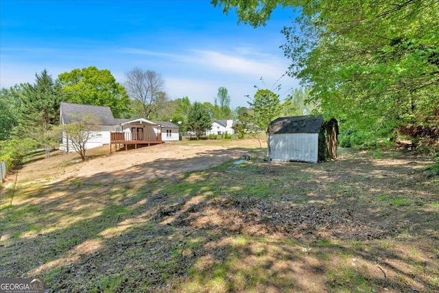 view of yard featuring a storage shed, an outbuilding, and a deck