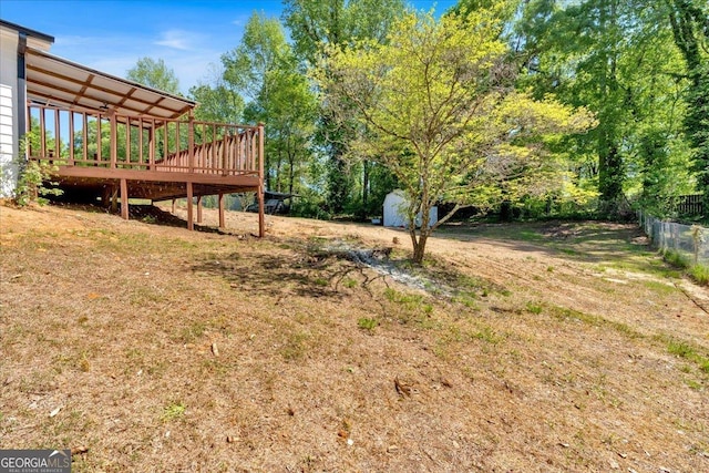 view of yard featuring an outbuilding, a shed, fence, and a deck