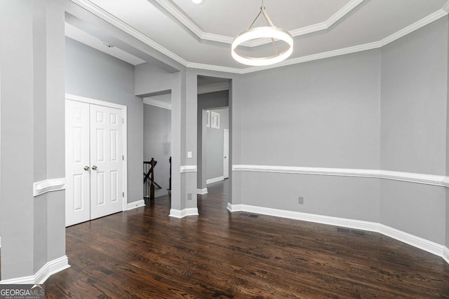 spare room featuring a tray ceiling, crown molding, wood finished floors, and baseboards