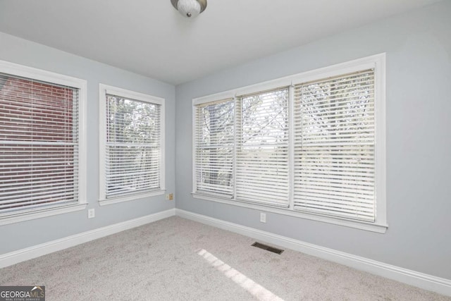 spare room with carpet flooring, visible vents, and baseboards