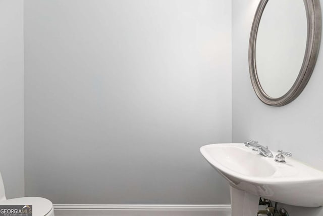 bathroom with toilet, a sink, and baseboards