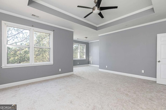 carpeted empty room with baseboards, a raised ceiling, crown molding, visible vents, and ceiling fan