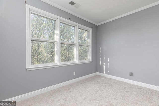 carpeted spare room featuring crown molding, baseboards, and visible vents