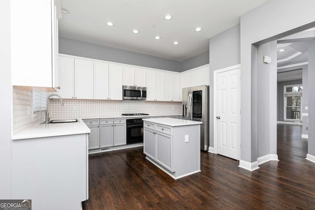 kitchen featuring tasteful backsplash, dark wood-style flooring, a kitchen island, black appliances, and a sink