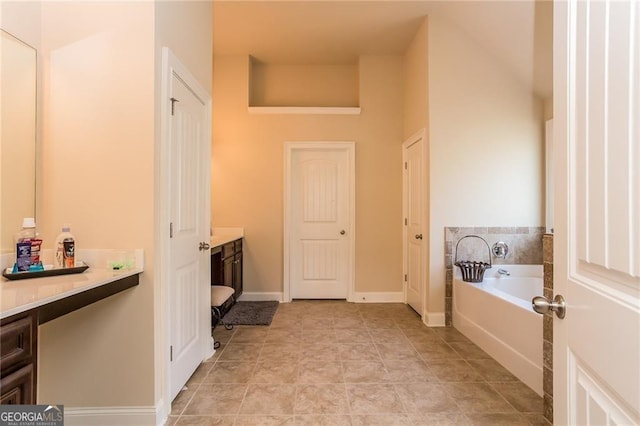 full bath featuring vanity, baseboards, and a bath