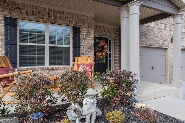 property entrance with covered porch, brick siding, and driveway