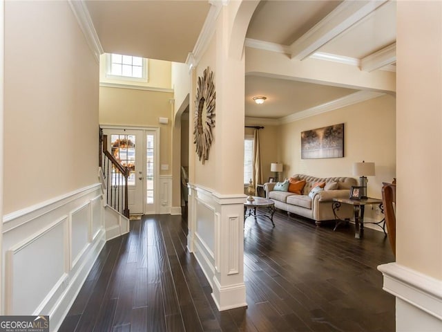 entrance foyer featuring wainscoting, arched walkways, ornamental molding, and dark wood-style flooring