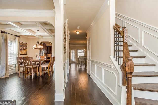 stairs featuring crown molding, beam ceiling, a decorative wall, arched walkways, and hardwood / wood-style flooring