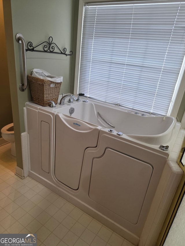 bathroom featuring tile patterned flooring, a bath, and toilet