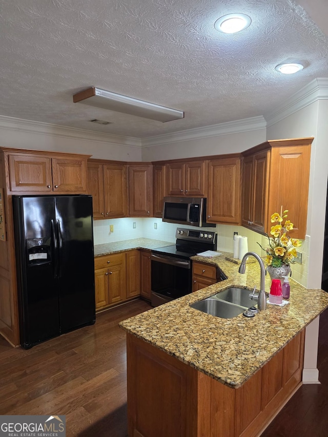 kitchen with a peninsula, brown cabinets, a sink, and appliances with stainless steel finishes