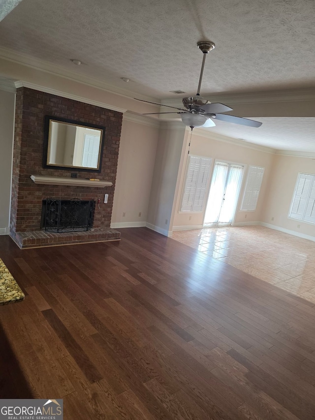 unfurnished living room with ornamental molding, a ceiling fan, a brick fireplace, and a textured ceiling