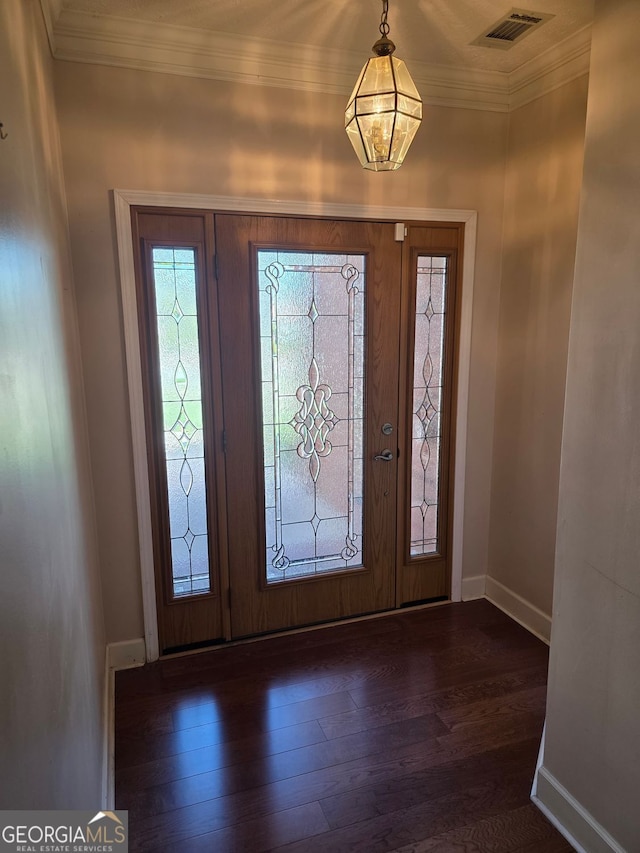 foyer with dark wood-type flooring, visible vents, baseboards, and crown molding