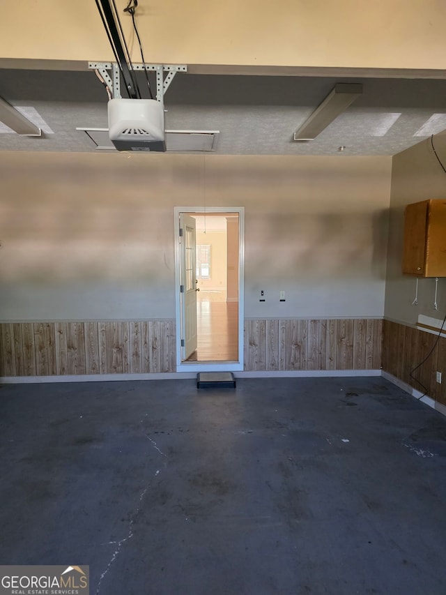 garage featuring wooden walls, a wainscoted wall, and a garage door opener