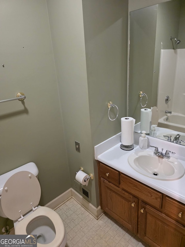 bathroom with toilet, vanity, baseboards, and shower / washtub combination