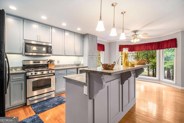 469 Kimberly Ct, Mcdonough, GA 30252 - kitchen with appliances with stainless steel finishes, gray cabinets, light wood-style flooring, ornamental molding, and stone counters