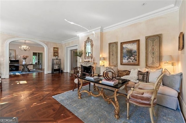 living area with baseboards, arched walkways, an inviting chandelier, ornamental molding, and a fireplace