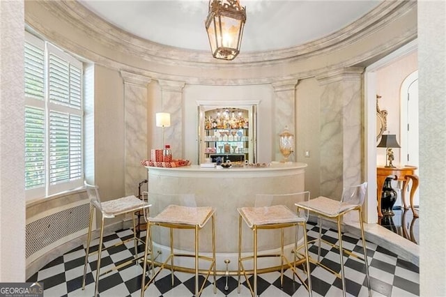 bar with bar, tile patterned floors, and decorative columns