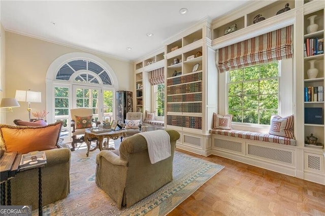 sitting room featuring ornamental molding, a wealth of natural light, and built in shelves
