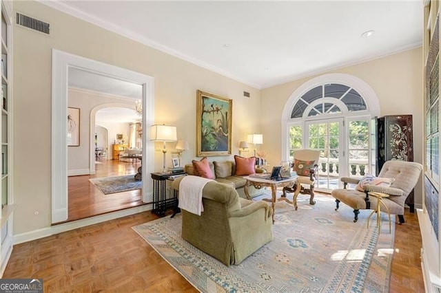 living room with arched walkways, visible vents, baseboards, and crown molding