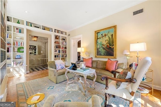 sitting room featuring wood finished floors, baseboards, built in shelves, and visible vents