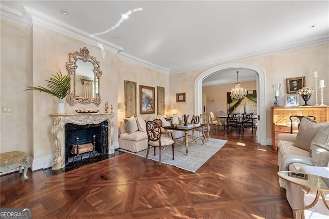 living area with baseboards, arched walkways, an inviting chandelier, a fireplace, and crown molding