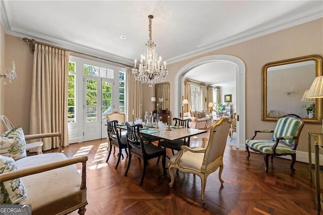 dining space with arched walkways, a notable chandelier, baseboards, and crown molding