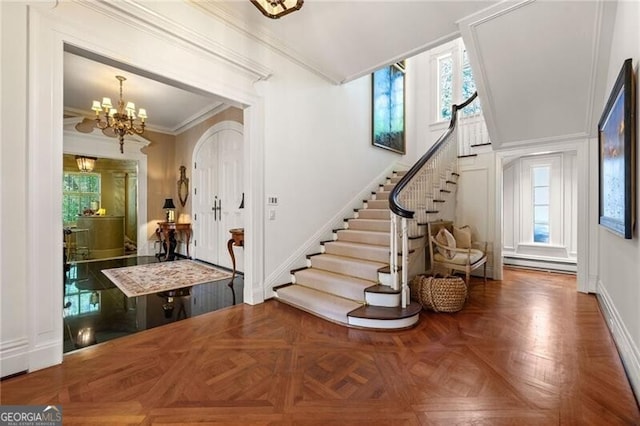 entryway with a wealth of natural light, stairway, ornamental molding, and an inviting chandelier