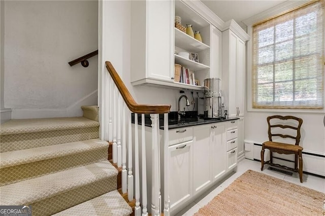 stairs with indoor wet bar and a baseboard radiator