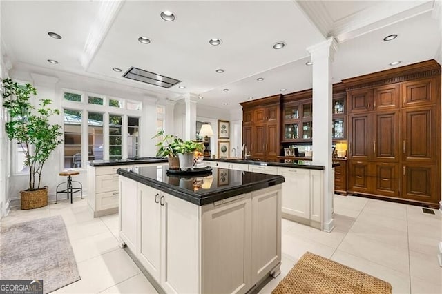 kitchen featuring recessed lighting, a peninsula, dark countertops, a kitchen island, and ornate columns