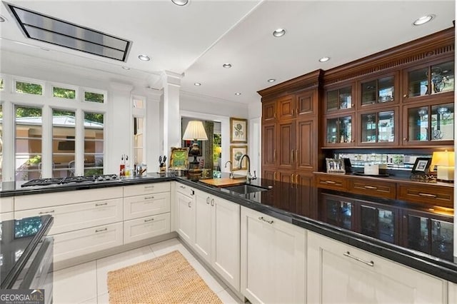 kitchen with light tile patterned floors, glass insert cabinets, a sink, recessed lighting, and stainless steel gas stovetop