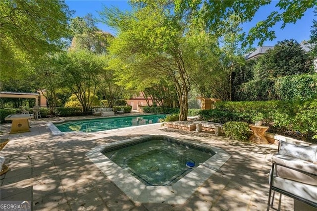 outdoor pool with a patio and an in ground hot tub