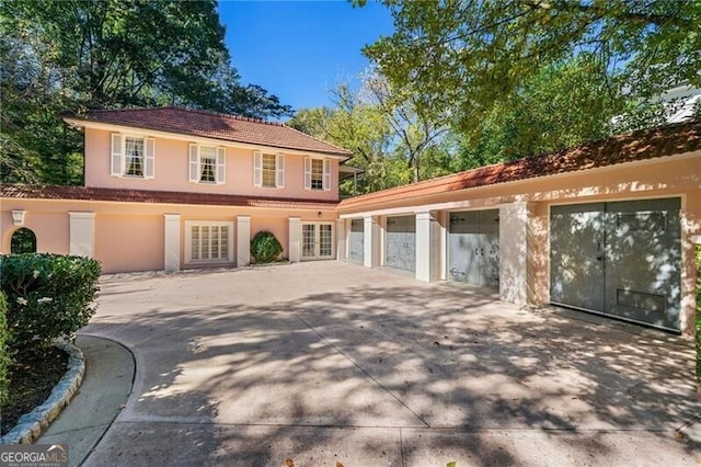 view of front of property featuring a tile roof, stucco siding, a garage, and concrete driveway