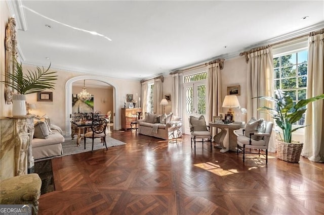 living room with arched walkways, plenty of natural light, and ornamental molding