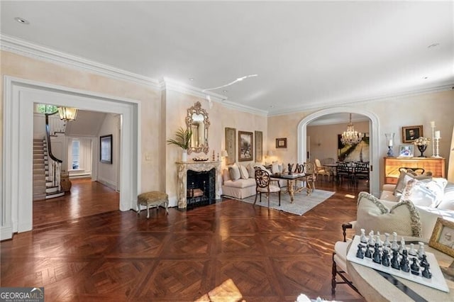 living area with arched walkways, an inviting chandelier, a fireplace, crown molding, and stairs