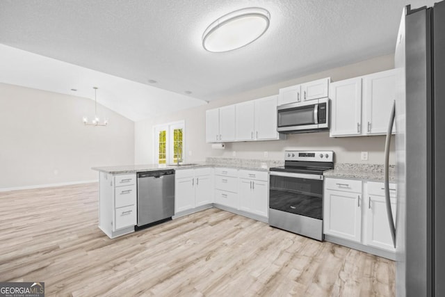kitchen with an inviting chandelier, a peninsula, white cabinetry, lofted ceiling, and stainless steel appliances