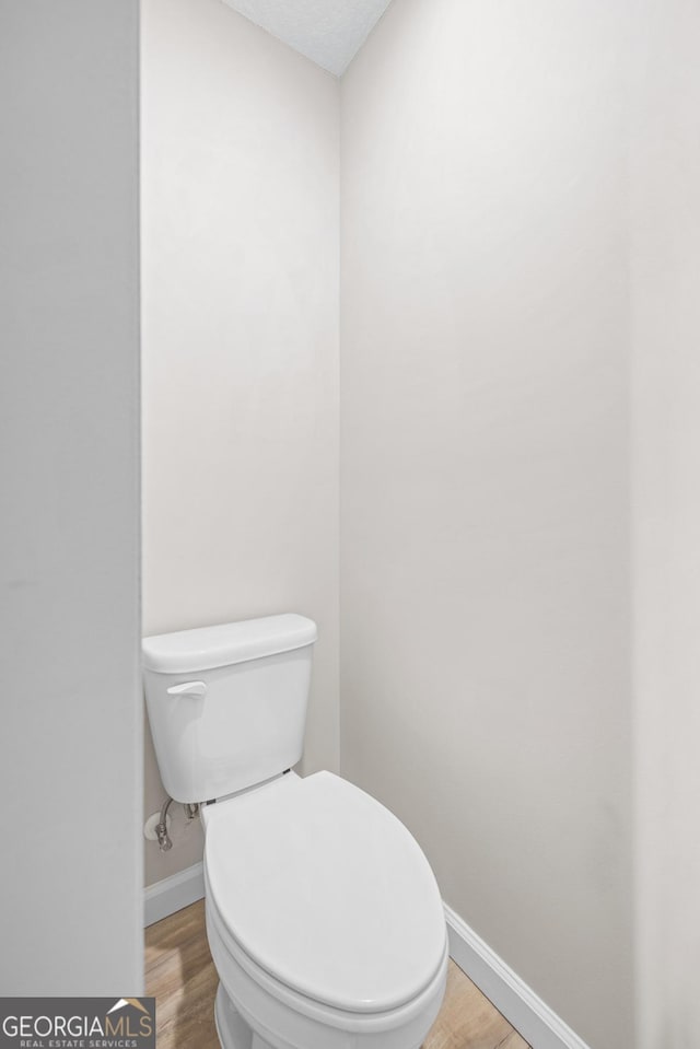 bathroom featuring toilet, wood finished floors, and baseboards