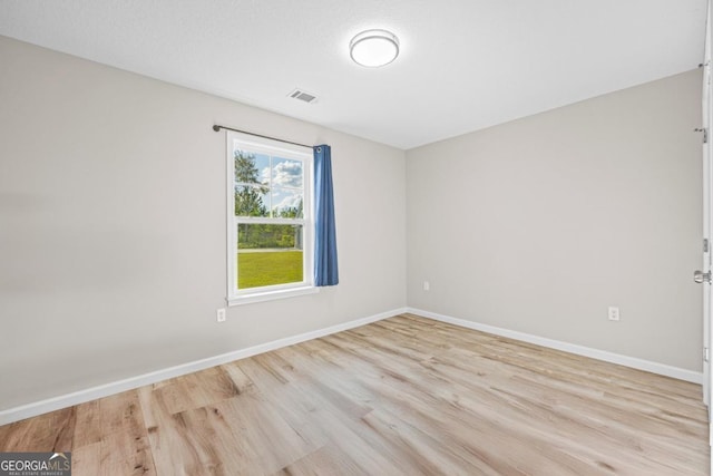 empty room with light wood-style flooring, baseboards, and visible vents