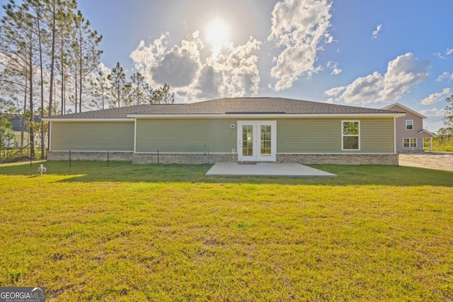 rear view of house featuring brick siding, french doors, a patio area, and a yard