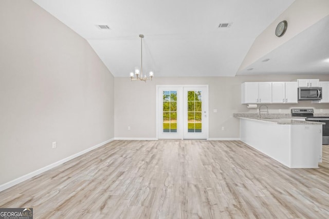 kitchen with light wood-type flooring, vaulted ceiling, appliances with stainless steel finishes, a sink, and baseboards