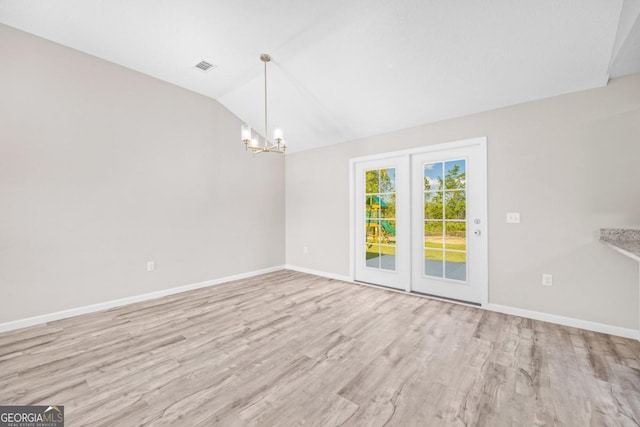 spare room featuring lofted ceiling, baseboards, an inviting chandelier, and wood finished floors