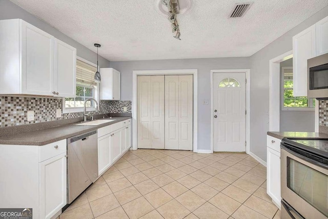 kitchen featuring dark countertops, a sink, backsplash, and appliances with stainless steel finishes