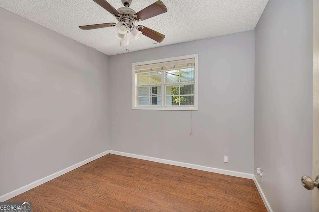 empty room with a textured ceiling, wood finished floors, ceiling fan, and baseboards